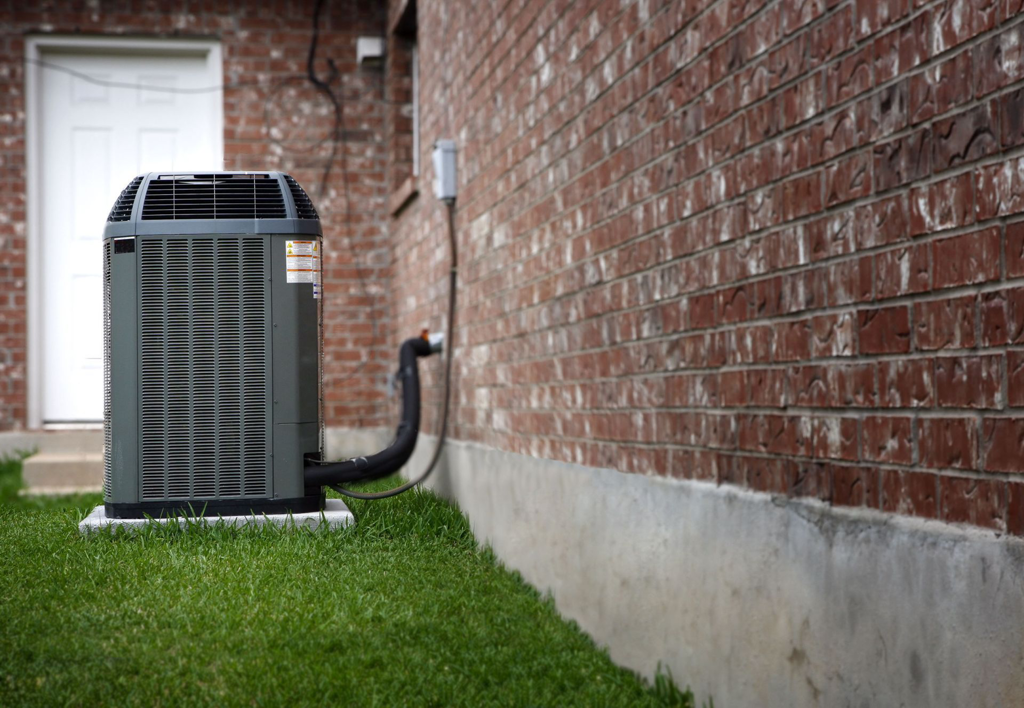 An outdoor air conditioning unit installed next to a residential brick house by McTeer's Heating & Cooling in Salisbury, MD.