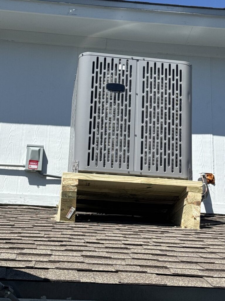 An outdoor AC condenser unit installed on a custom wooden platform on a roof by Gibson's Air Conditioning & Heating in Corpus Christi, TX.
