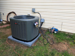 An outdoor AC unit being serviced with gauges and a vacuum pump by Fred's Heating And Cooling in Charlotte, NC
