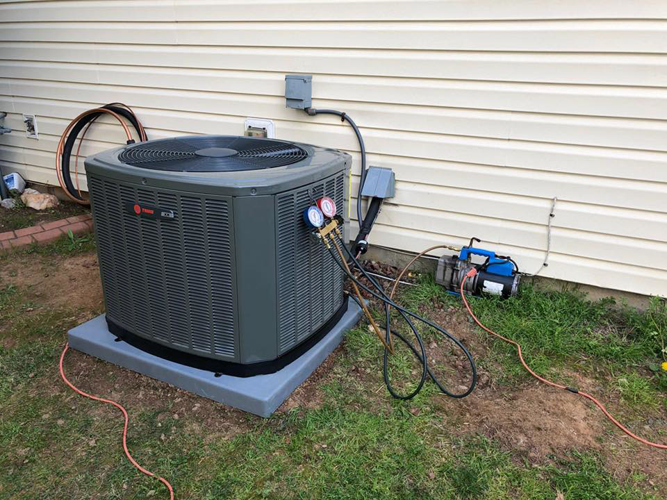 An outdoor AC unit being serviced with gauges and a vacuum pump by Fred's Heating And Cooling in Charlotte, NC