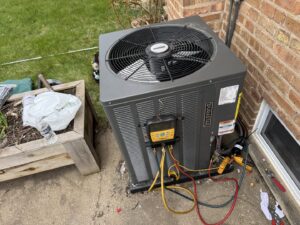 An outdoor AC unit undergoing service and maintenance by Etek Refrigeration Heating and Cooling, Inc. in Chicago, IL.