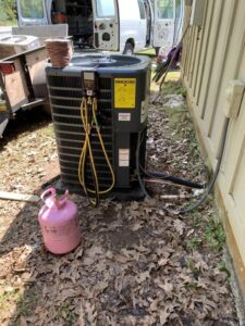 An outdoor air conditioning unit being serviced with gauges and a refrigerant tank by Netherland Air Conditioning LLC in Mobile, AL.
