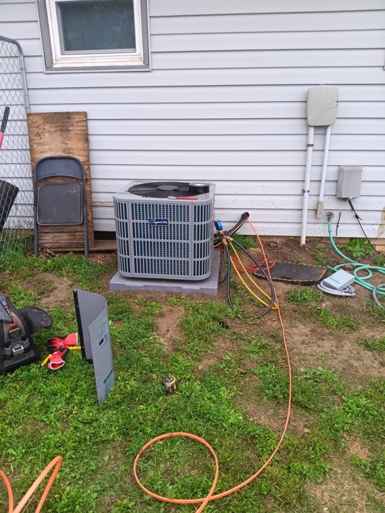 An outdoor air conditioning unit being serviced with gauges and tools by Preferred Heating & Air in Bismarck, ND.