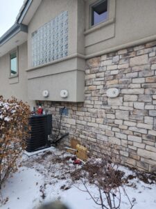 An outdoor air conditioning unit being serviced or installed during winter by D & D Heating & Air in Brighton, CO.