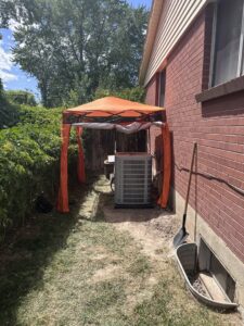 An outdoor air conditioning unit under a protective canopy by ICare Heating & Air in Millcreek, UT.