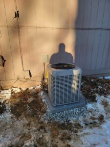 An outdoor air conditioning unit during winter, serviced by Working Wolves Heating & Cooling LLC in Lawrence, KS.