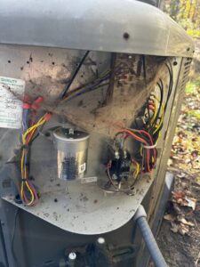 An open panel of an outdoor AC unit showing wiring and components during an inspection by OnPoint Heating and Air in Commerce City, CO.