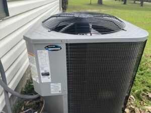An outdoor air conditioning unit featuring the Total Living Comfort business sticker, installed in Irvington, AL.