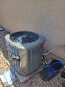 An outdoor AC condenser unit with refrigerant gauges connected, indicating service by Az AC and Heat Services in Queen Creek, AZ.