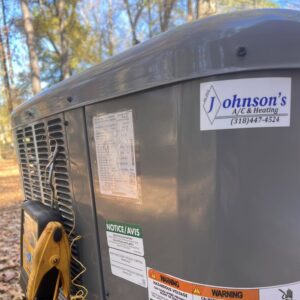 A close-up of an outdoor air conditioning unit with a Johnson's A/C & Heating service sticker in Alexandria, LA.