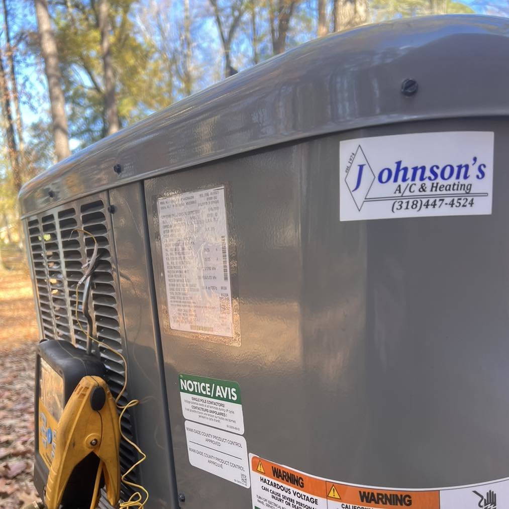 A close-up of an outdoor air conditioning unit with a Johnson's A/C & Heating service sticker in Alexandria, LA.