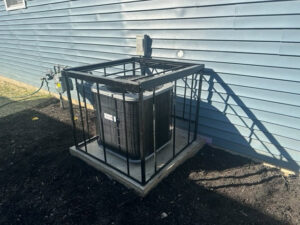 An outdoor AC unit with a protective metal cage installed by Fellowship Heating and Cooling in Indianapolis, IN.