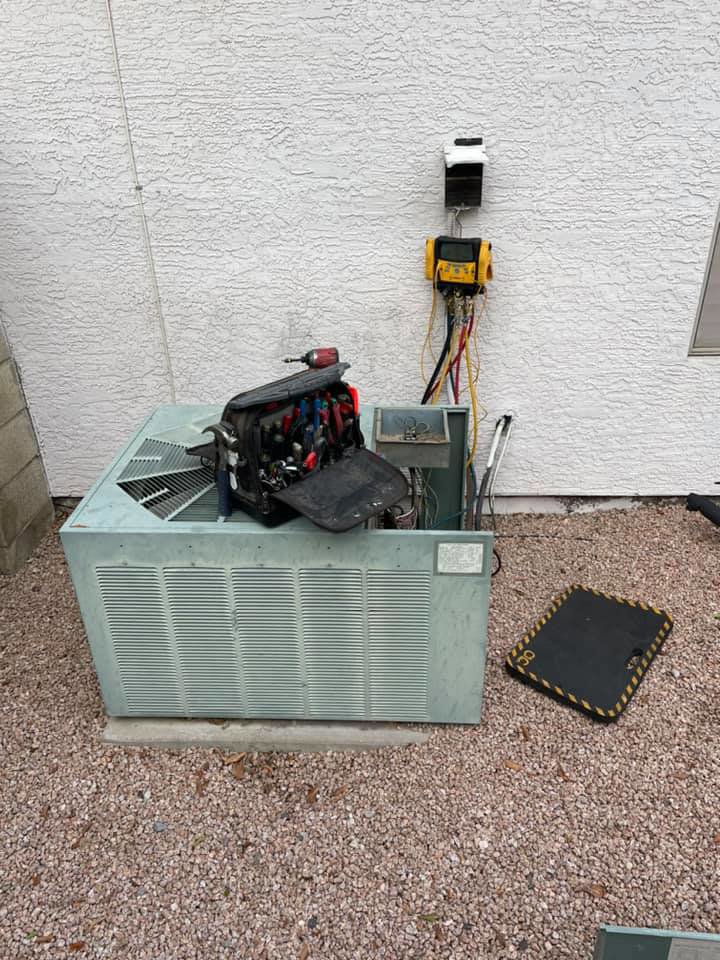 An outdoor AC unit with tools and gauges connected for service by Mountainside Air in Phoenix, AZ.