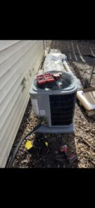 An outdoor air conditioning unit with tools on top, indicating ongoing or recently completed service by Holzer Heating And Cooling in Savage, MN