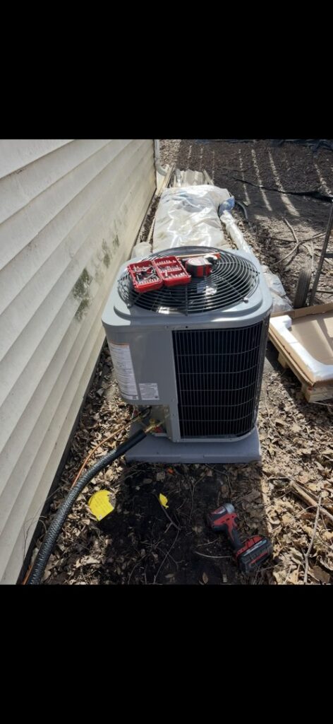 An outdoor air conditioning unit with tools on top, indicating ongoing or recently completed service by Holzer Heating And Cooling in Savage, MN