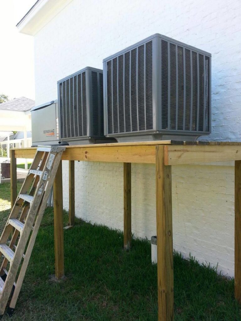 Two outdoor AC units and a generator installed on a raised wooden platform by McGuffee's Air Conditioning and Heating in Gulfport, MS
