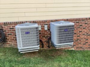 Two Carrier outdoor AC units installed next to a brick house by Advanced HVAC and Plumbing in Morgantown, WV.