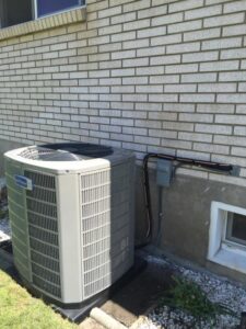 An outdoor air conditioner unit installed next to a residential brick wall by Any Climate Mechanical HVAC in Sandy, UT.
