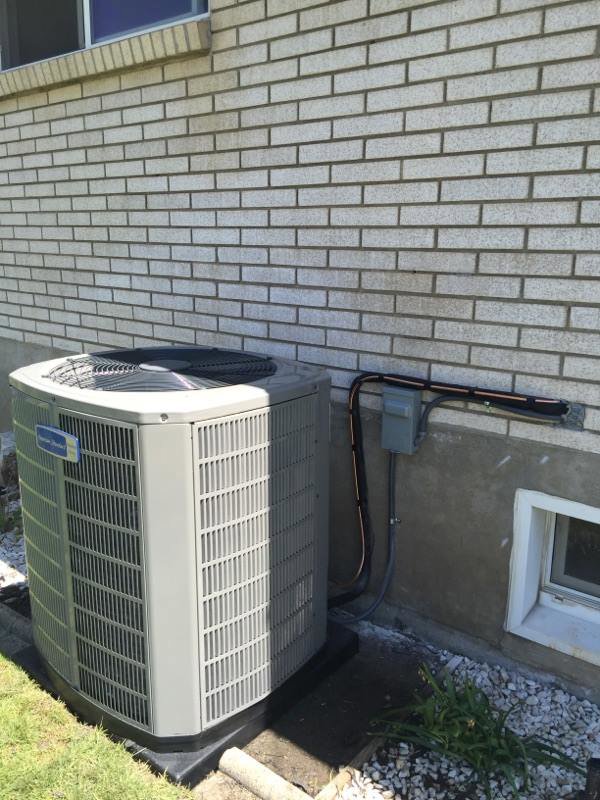 An outdoor air conditioner unit installed next to a residential brick wall by Any Climate Mechanical HVAC in Sandy, UT.