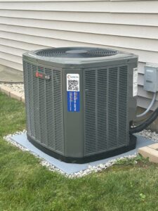 An outdoor Trane air conditioner unit installed next to a residential home by Air For You Heating and Air in Joliet, IL.