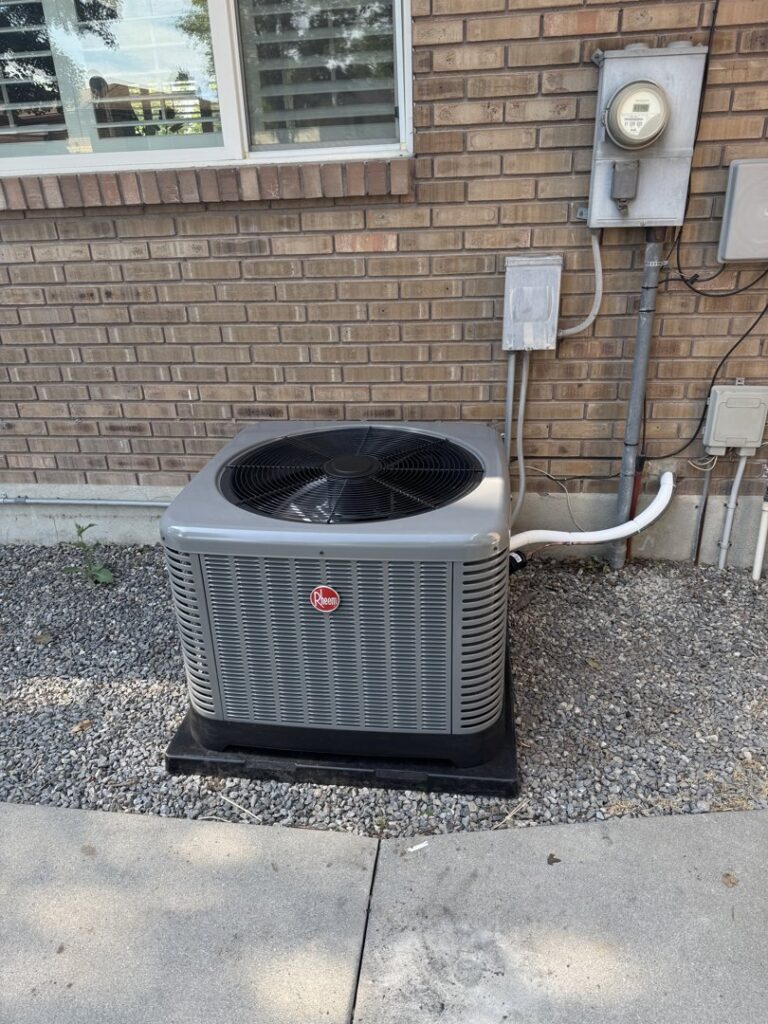 An outdoor air conditioner unit installed next to a brick wall by Peterson Heating & Cooling in Mound City, KS.