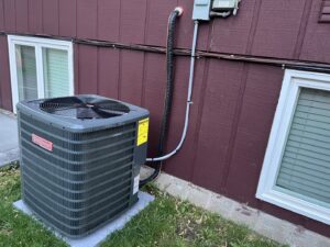 An outdoor Goodman air conditioning unit installed next to a residential building by Advanced Heating & Cooling in St. Cloud, MN.