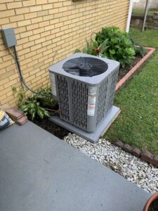 An outdoor air conditioning condenser unit installed next to a brick house by Berkshire Heating and Cooling in Pittsburgh, PA