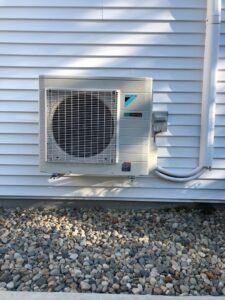 An outdoor Daikin air conditioning unit installed on a home by Derry Plumbing & Heating in Derry, NH.