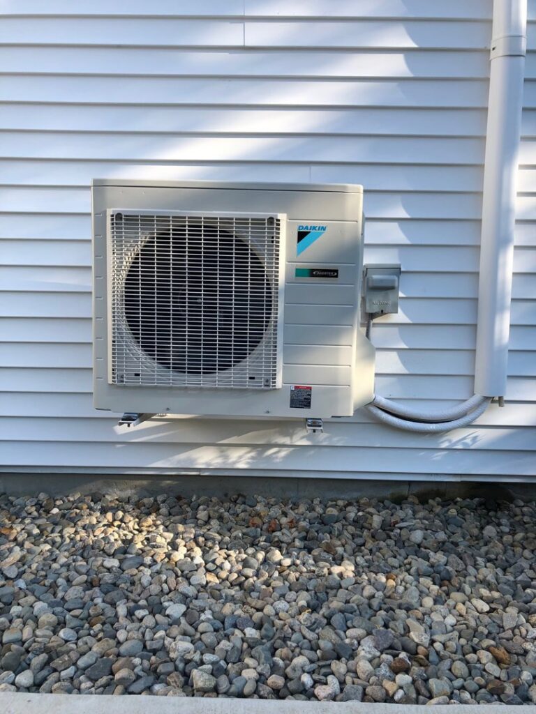 An outdoor Daikin air conditioning unit installed on a home by Derry Plumbing & Heating in Derry, NH.