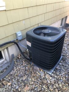 An outdoor air conditioning condenser unit installed next to a residential building by EPIC Heating and Air in Loveland, CO