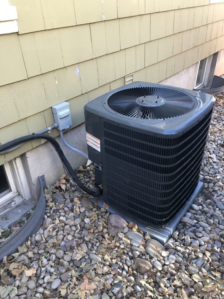 An outdoor air conditioning condenser unit installed next to a residential building by EPIC Heating and Air in Loveland, CO
