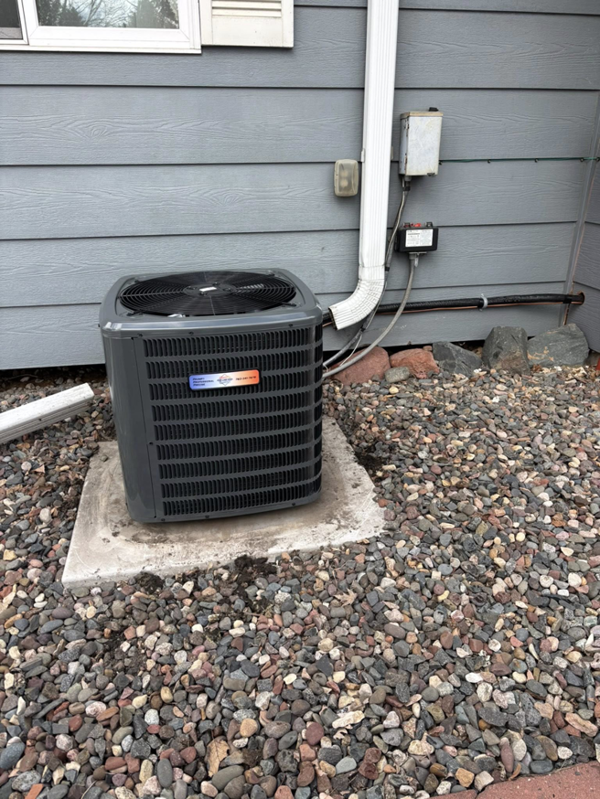 An outdoor air conditioning condenser unit installed on a concrete pad by Fine Line HVAC LLC for cooling services in Isanti, MN.
