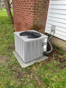 An outdoor AC unit installed next to a residential building by Frank N Frank Mechanical Contractors in Rochester, NY.