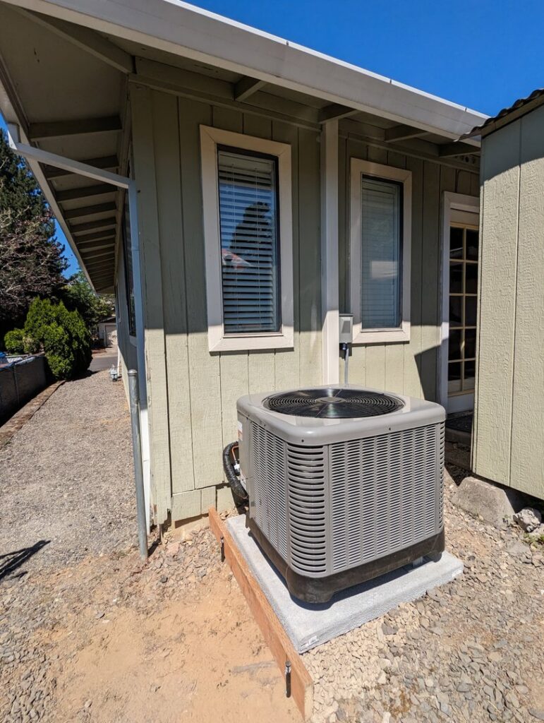 An outdoor air conditioning unit newly installed next to a home by Gresham Heating and Air Conditioning in Wood Village, OR.