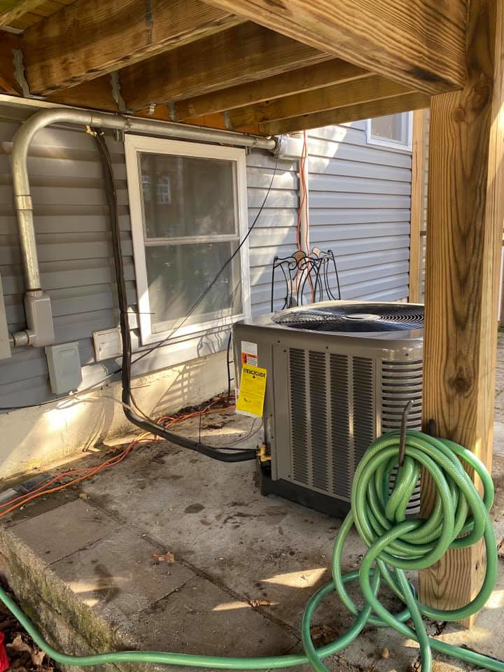 An outdoor air conditioning unit installed next to a residential building by Virtues Mechanical LLC in Baltimore, MD.
