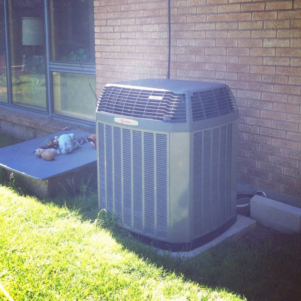 An outdoor air conditioning unit installed next to a brick house by Access Heating & Air Conditioning in Fredericksburg, VA
