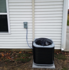 An outdoor air conditioning unit installed next to a residential home by Manz Heating and Cooling in Fort Wayne, IN.