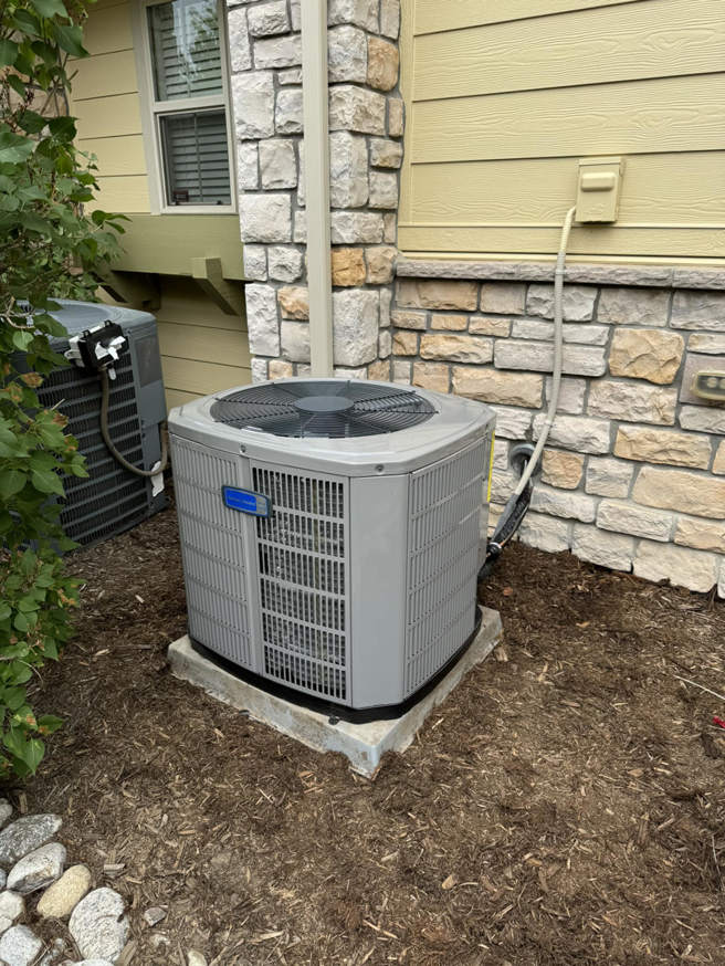 An outdoor air conditioning unit installed next to a residential building by Nexus Heating & Air in Denver, CO.