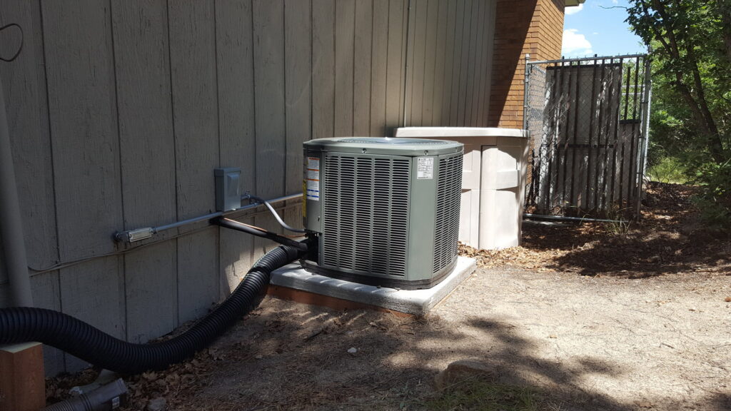 An outdoor air conditioning unit installed next to a residential building by Reliable Heating & Cooling LLC in Colorado Springs, CO