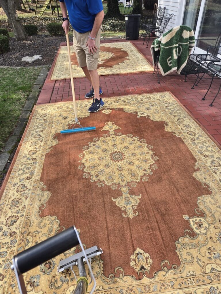 A professional cleaning large area rugs outdoors by On The Spot Carpet and Upholstery Cleaning in Warren, MI.