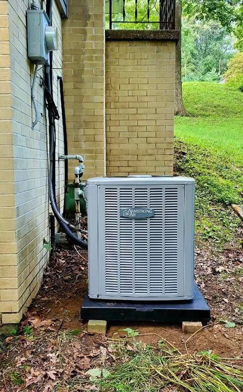 An outdoor Armstrong Air conditioning unit installed next to a brick building by Adams Heating and Cooling in Schenectady, NY