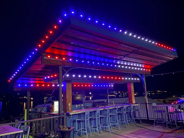 Vibrant red and blue string lights illuminating an outdoor bar patio installed by Get Lit KC & LOZ in Kansas City, KS.