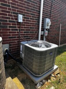 Outdoor Carrier AC unit professionally installed next to a brick wall by Benavidez Heating & Air Conditioning In, Arlington, TX.