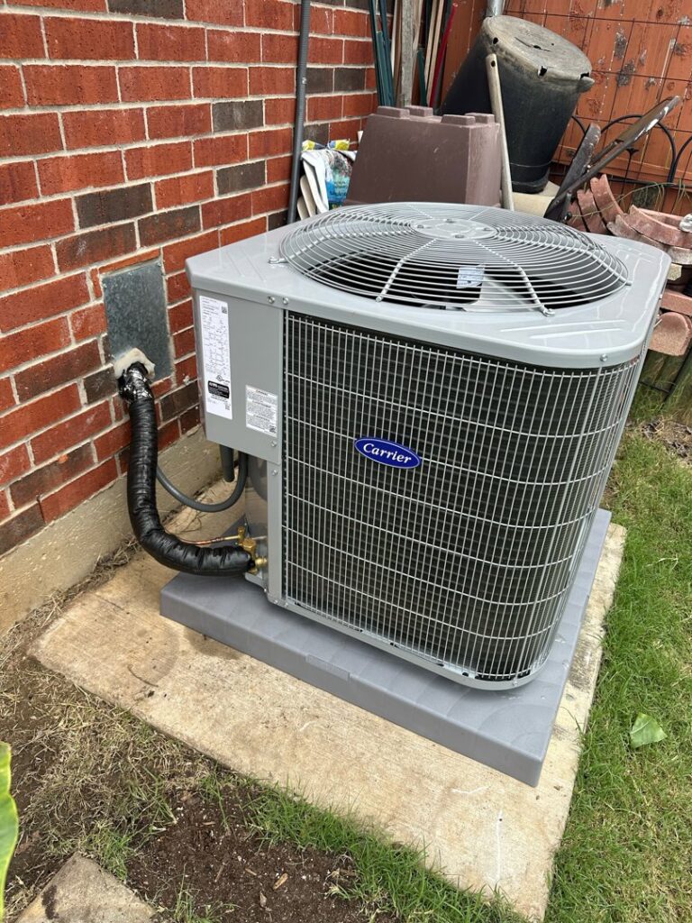A newly installed outdoor Carrier AC unit next to a brick wall by BV Air Conditioning & Heating in Dallas, TX.