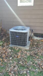 An outdoor Carrier air conditioning unit installed next to a residential building by Custom Climates in Iowa City, IA.