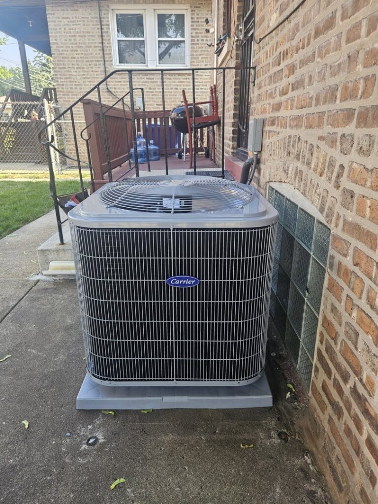 An outdoor Carrier air conditioning unit installed next to a brick building by Mid-City HVAC, INC. in Chicago, IL.