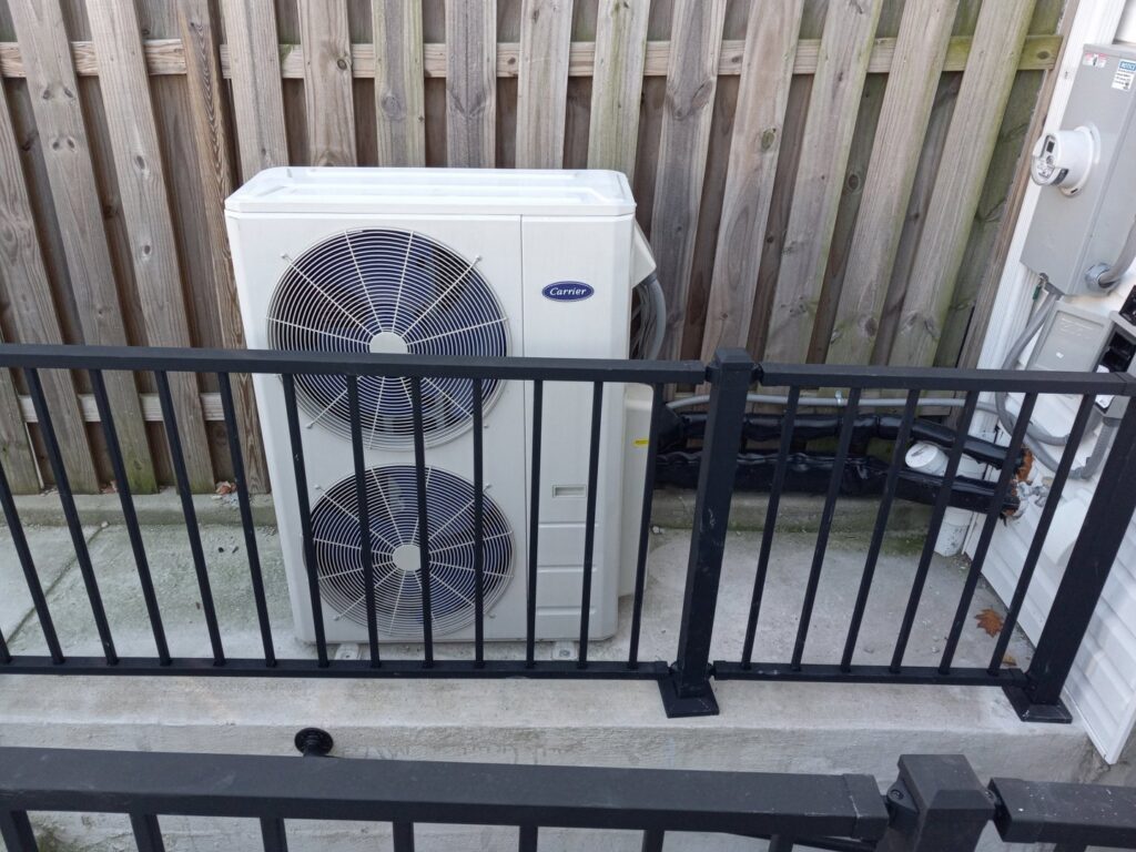 An outdoor Carrier brand heat pump or AC condenser unit, ready for installation or service by Simply Home Service in Gaithersburg, MD.