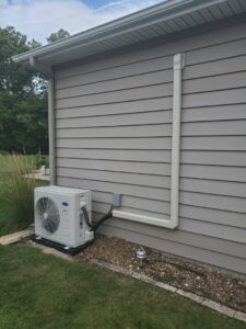 An outdoor Carrier mini-split air conditioning unit installed on the side of a house by Custom Climates in Iowa City, IA.