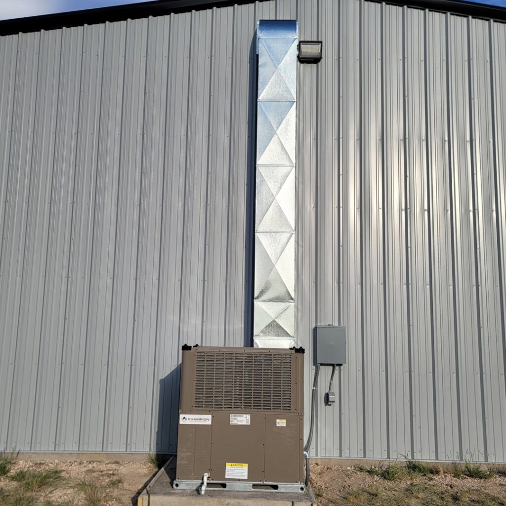 An outdoor Champion HVAC unit and vertical ductwork installed on a commercial building by After Hours Heating & Air Conditioning LLC in Chesapeake, VA.