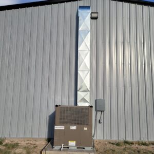 An outdoor Champion HVAC unit and vertical ductwork installed on a commercial building by After Hours Heating & Air Conditioning LLC in Chesapeake, VA.